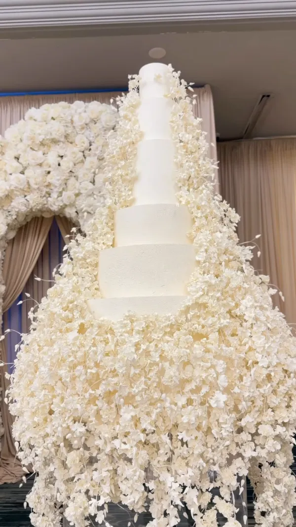 Towering wedding cake wrapped in cascading white florals