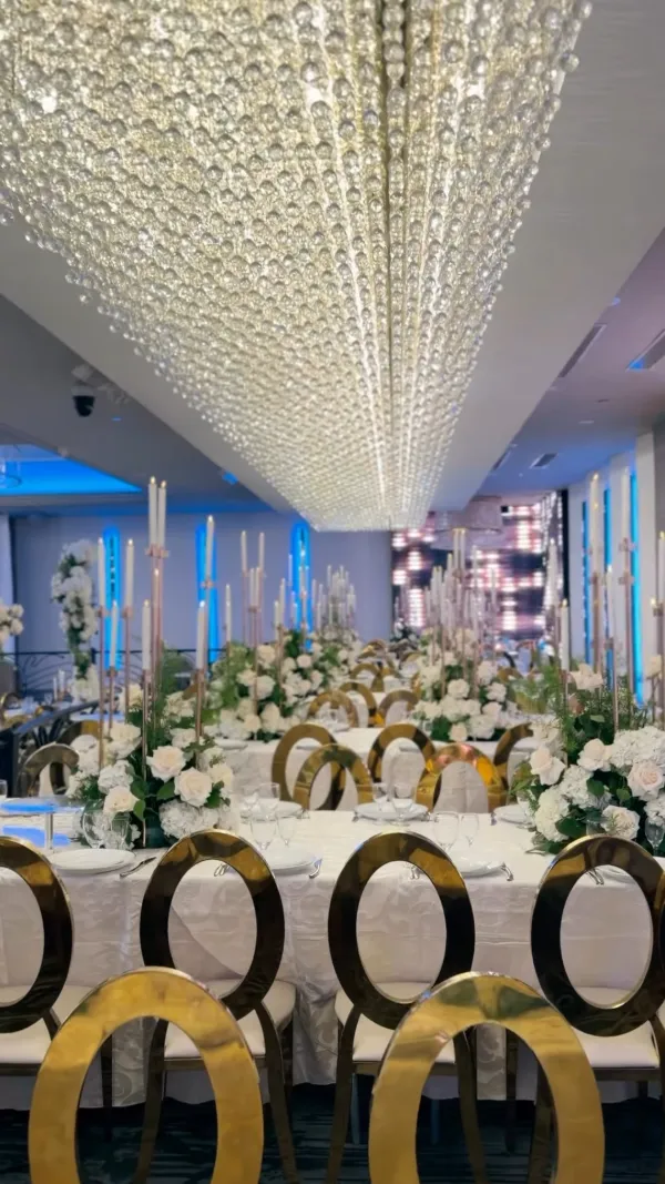 Crystal ceiling above gold-rimmed chairs and white florals