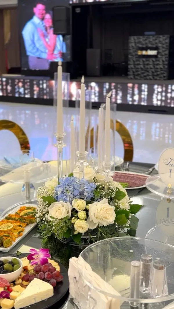 Table set with cheeses, grapes, appetizers and a white rose centerpiece